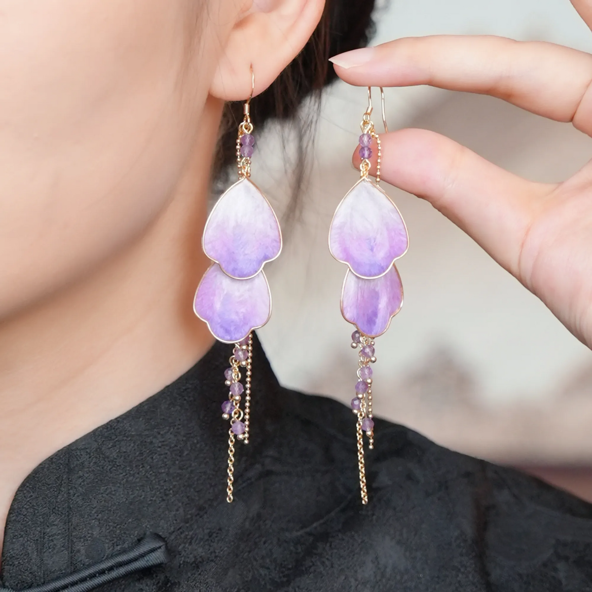 Wisteria Prelude Ronghua drop earrings with purple mulberry silk petals and delicate gold tassels displayed on a jewelry stand