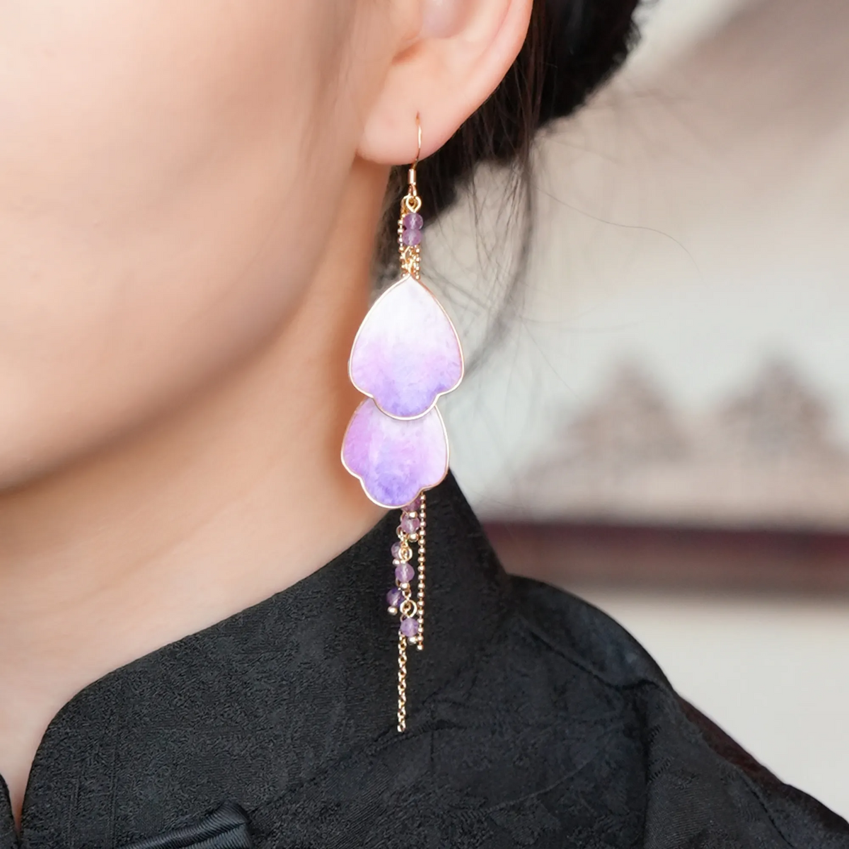 Close-up of Wisteria Prelude Ronghua drop earring worn on the ear with purple mulberry silk petals and gold details